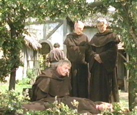 Brother Cadfael examines the body of the monk sent to pay the Rose Rent